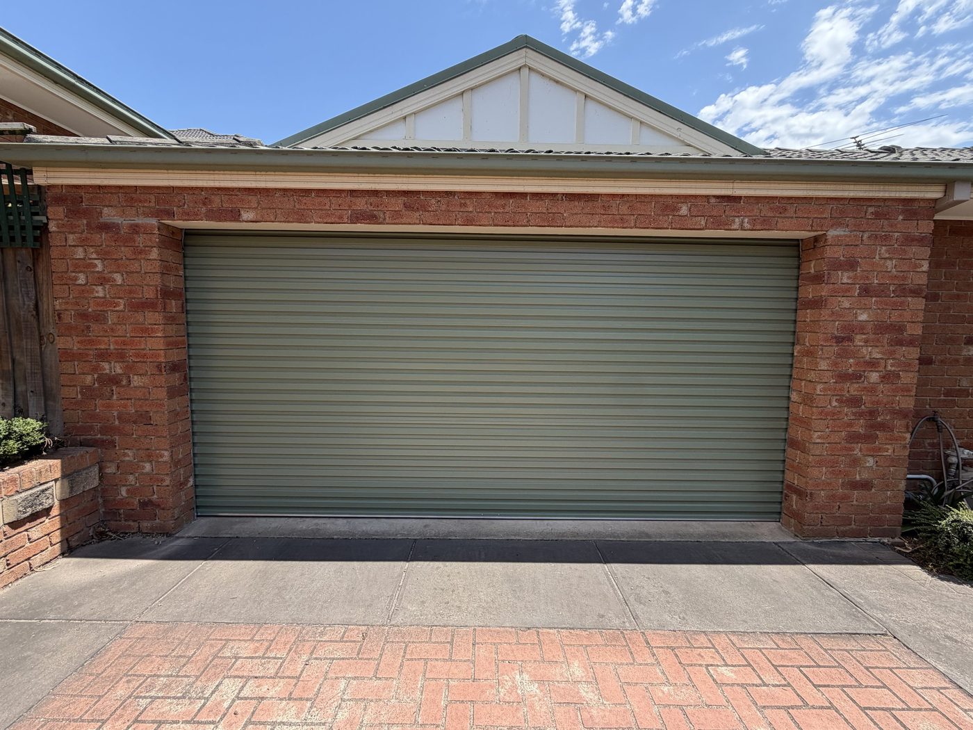 Green roller door on a red brick garage